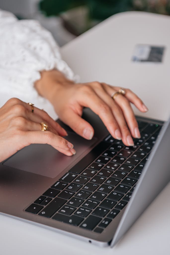 Hands of a woman typing on a laptop keyboard indoors, faceless marketing