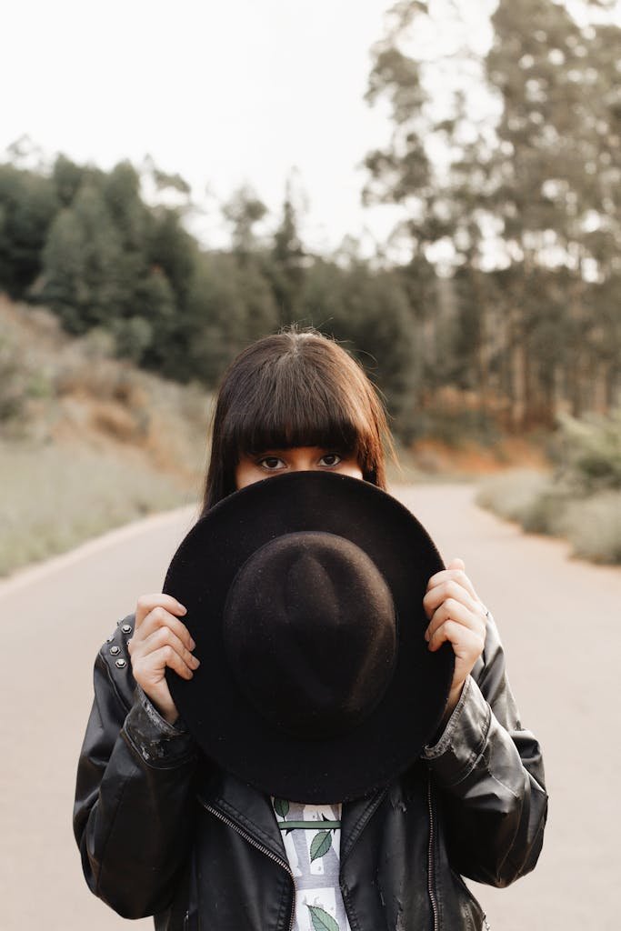 woman hiding behind a hat